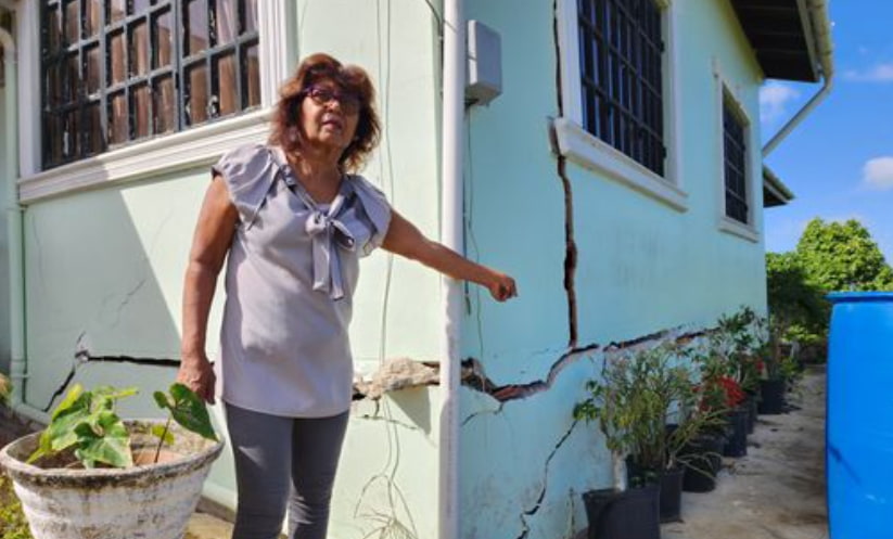 Bachan pints to the cracks in her home due to landslip. (Credits: T&T Guardian, Facebook)